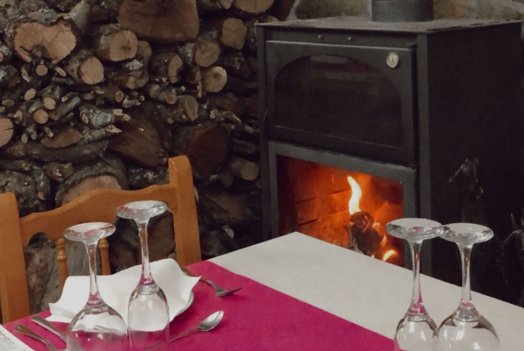 Mesa preparada junto a chimenea encendida en ambiente acogedor de restaurante